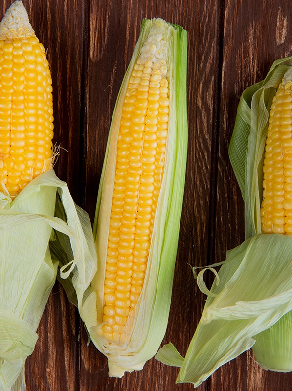 top view of corns with shell on wooden background 2